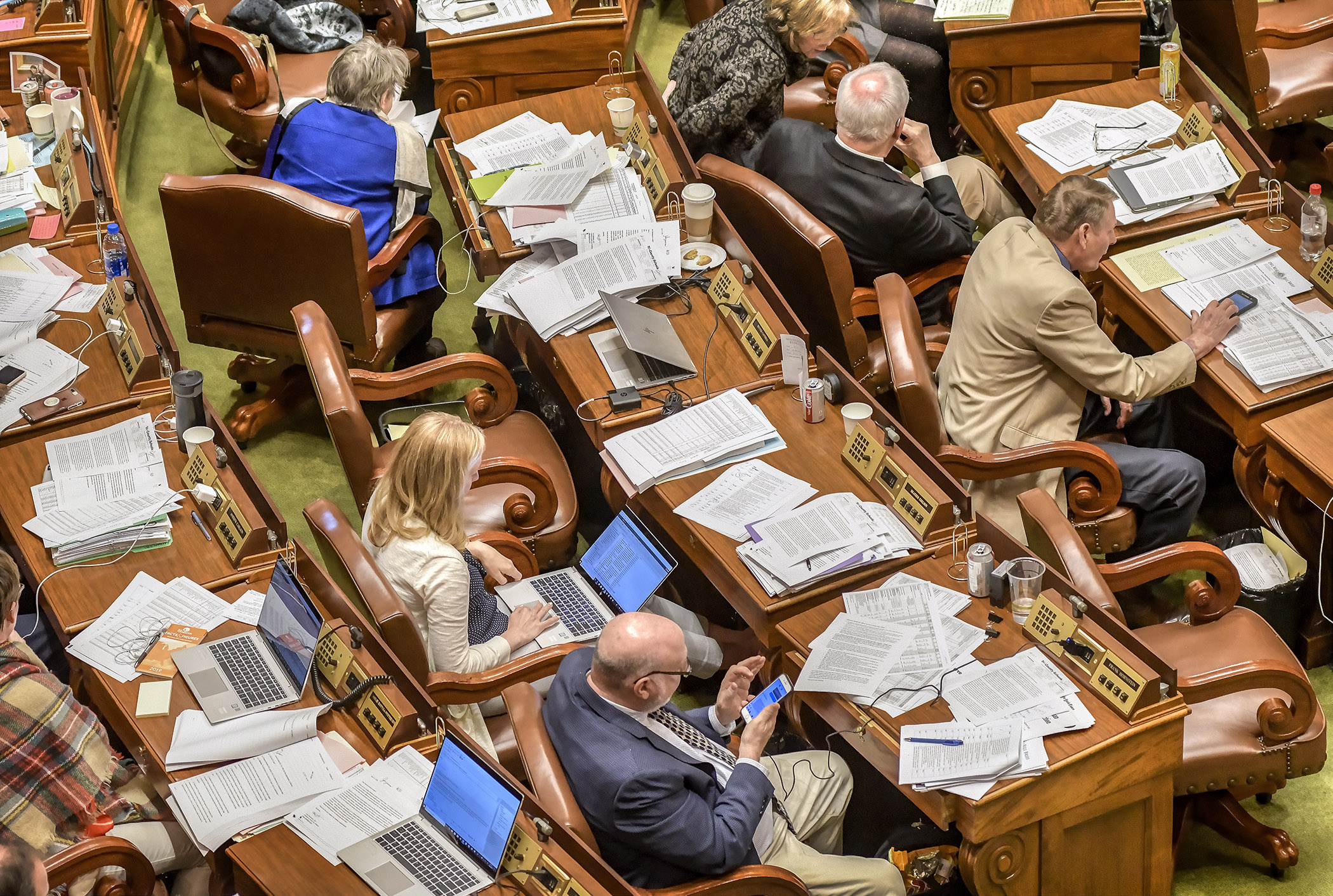 Amendments and paperwork from omnibus bills accumulate on members’ desks during a marathon floor session Tuesday evening. Photo by Andrew VonBank